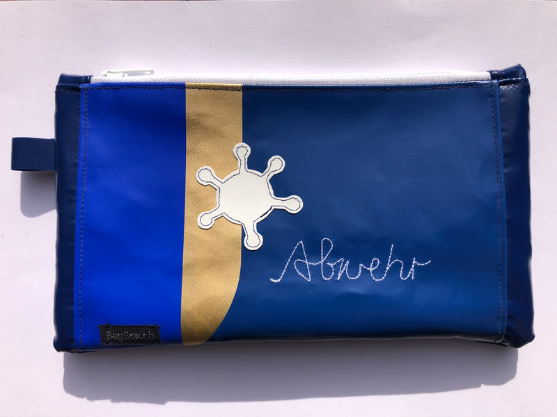 Maskentäschli aus gebrauchtem Werbebanner. Mit Aufschrift Abwehr in den Farben blau/ gold/ weiss.